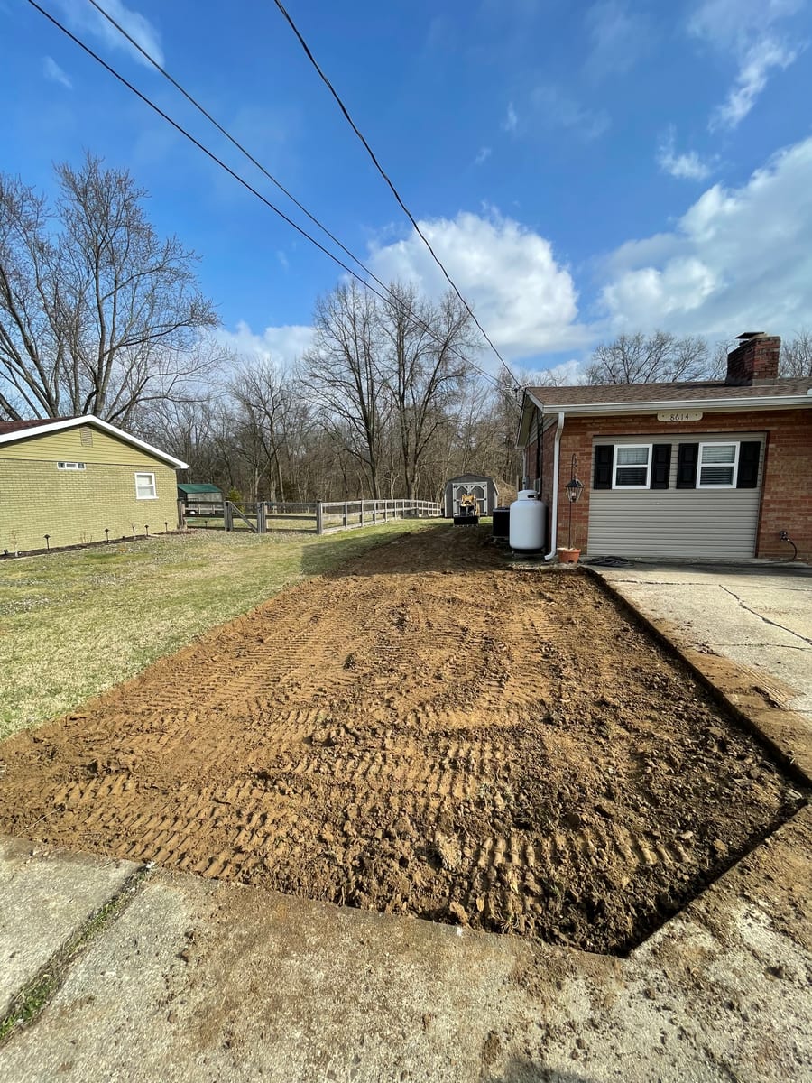 Excavator grading dirt next to structure