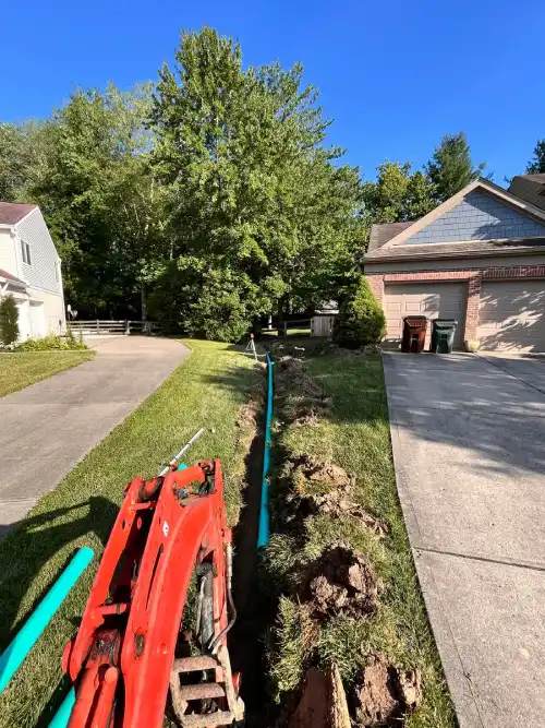 French drain pipe installation between residential driveways.